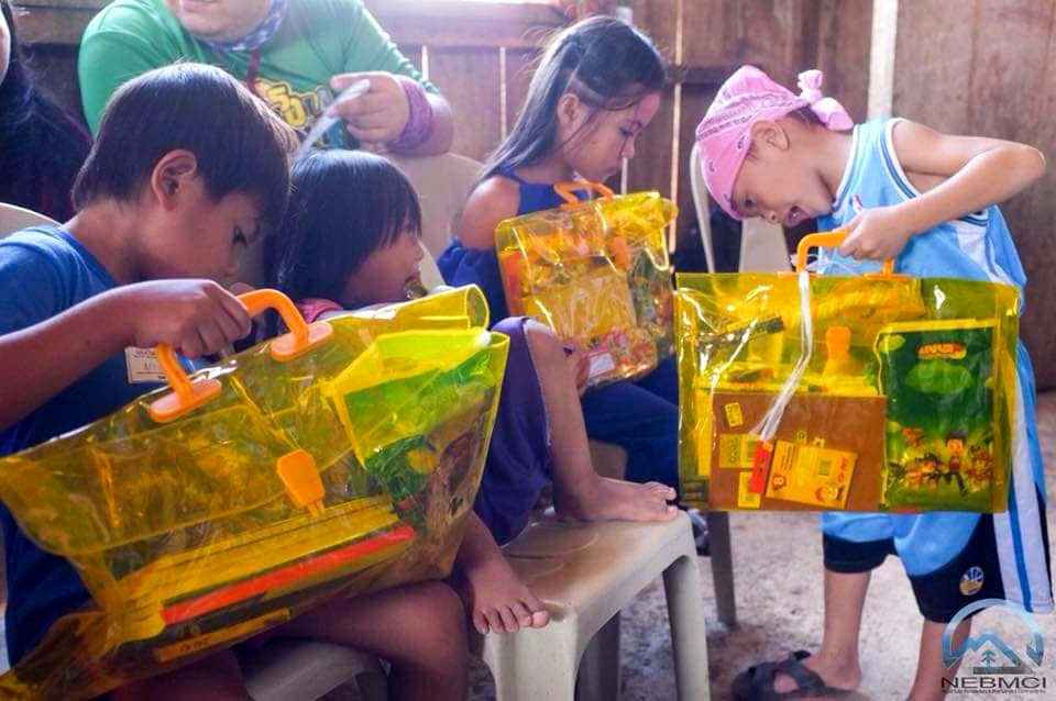 Excited kids with transparent bags full of school supplies.